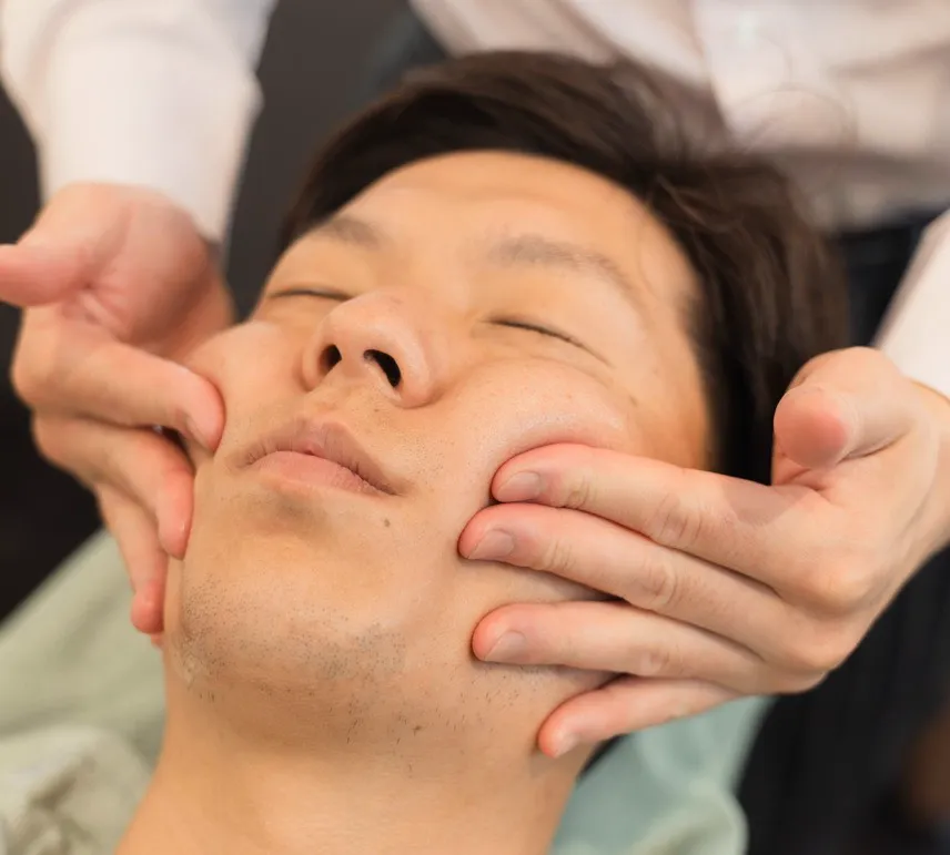 30代男性がフェイシャルマッサージを受けている画像