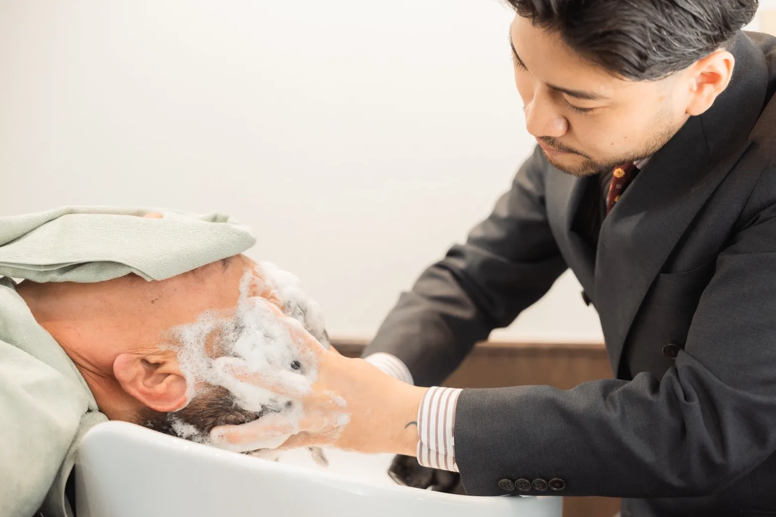 30~40代男性が気持ちよさそうにヘッドスパを受けている画像