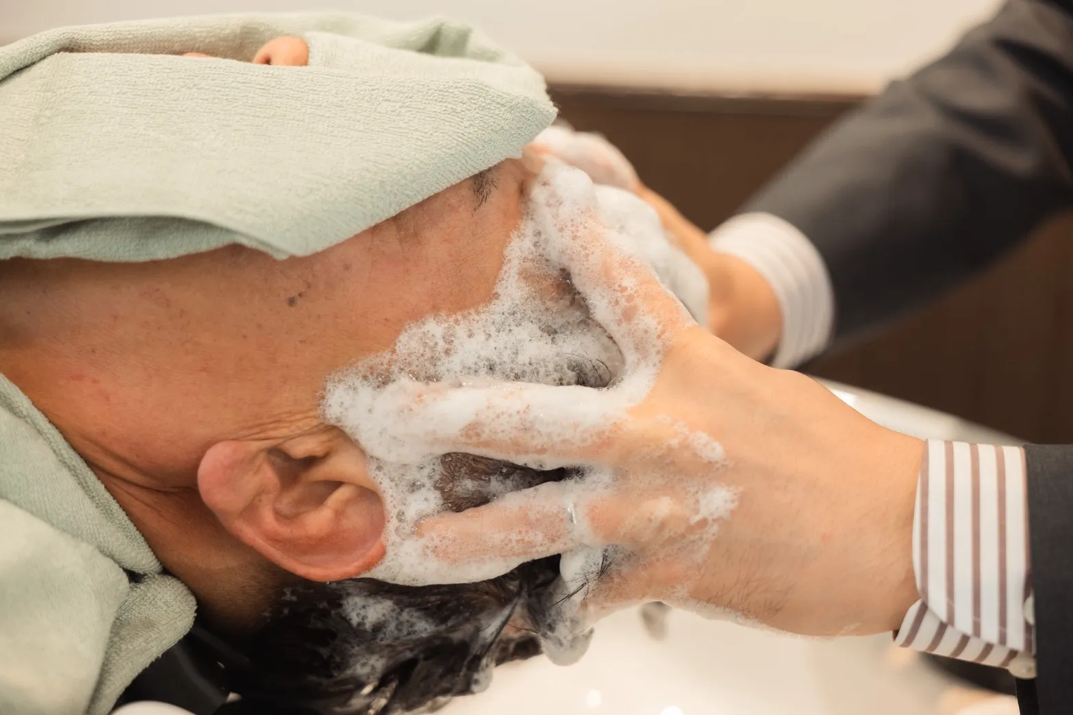 30～40代のビジネスマンがヘッドスパで気持ちよさそうにもみほぐしを受けている画像
