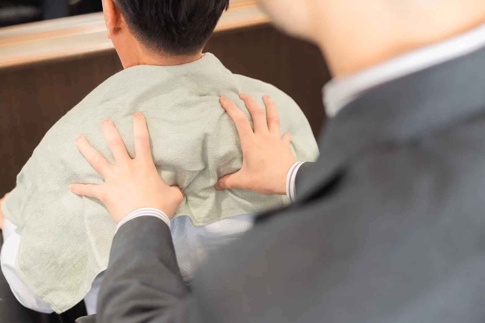 30～40代のビジネスマンが方の揉みほぐしをモーリーズバーバーショップで受けている画像